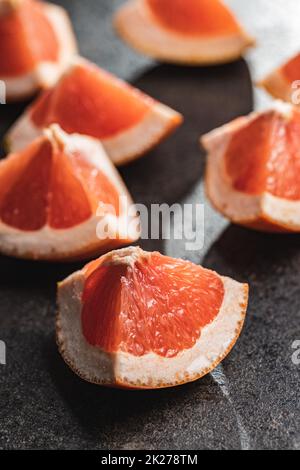 Sliced citrus fruit. Chopped fresh grapefruit on black table. Stock Photo