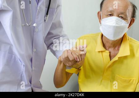 doctor is holding an elderly man's hand to cheer him up. Stock Photo