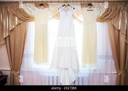 bride and bridesmaids dresses hanging on hangers Stock Photo