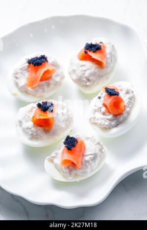 boiled eggs filled with tuna fish spread and smoked salmon and  black caviar on the top Stock Photo