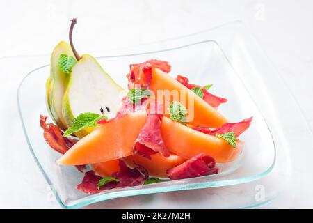 melon cantaloupe and pear with  proscutto and mint leaves Stock Photo