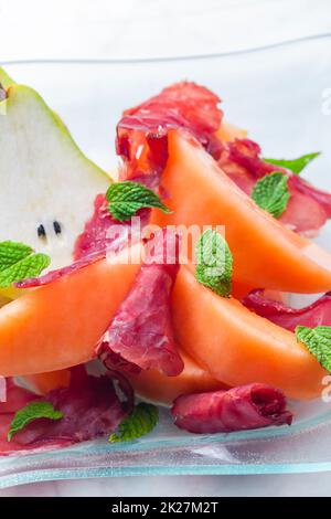 melon cantaloupe and pear with  proscutto and mint leaves Stock Photo