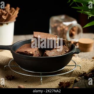 pieces of baked brownie in a metal black frying pan on the table Stock Photo