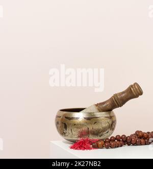 copper singing bowl and wooden clapper on a white table. Musical instrument for meditation, relaxation, various medical practices related to biorhythms, normalization of mental health Stock Photo