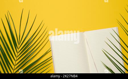 open notebook with blank white sheets on a yellow background, top view. Stock Photo