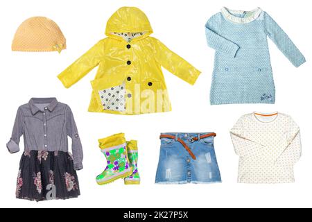 Collage set of little girl clothes isolated on a white background. The collection of a jeans or denim skirt, a rain jacket, a blouse, dresses, a hood or cap and yellow rubber boots. Fashionable kids outfit. Stock Photo