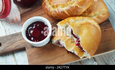 Cherry Pies stuffed with berries cherry, bowl with cherry jam. Homemade sweet pies from yeast dough freshly  baked in oven Stock Photo