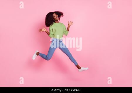Full length photo of impressed funky lady wear green sweater jumping high empty space isolated pink color background Stock Photo
