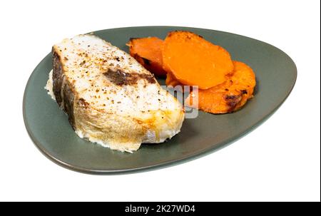 baked cod steak with boiled sweet potato slices on green plate isolated ...