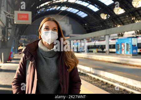 Portrait of business woman waiting train wearing medical protective mask at train station in winter Stock Photo