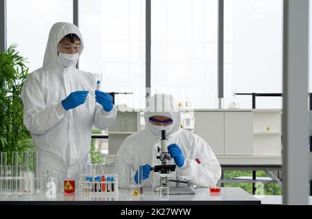 Epidemiological researchers in virus protective clothing are looking at blood samples of patients infected with Covid-19. Omicron strain testing process, Coronavirus disease 2019. Stock Photo