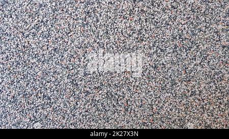Gray concrete surface with multi-colored marble chips. Foreground. Dark gray marble chips. Wall, facade trimmed with marble chips Stock Photo