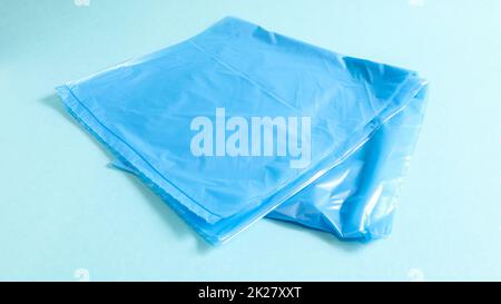 One torn plastic garbage bag in blue on a blue background. A bag that is designed to accommodate garbage in it and is used at home and placed in various garbage containers. Stock Photo