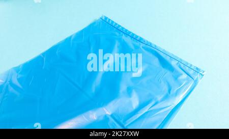 One torn plastic garbage bag in blue on a blue background. A bag that is designed to accommodate garbage in it and is used at home and placed in various garbage containers. Stock Photo