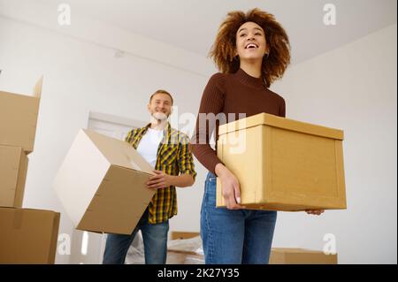 Happy multiethnic couple carrying cardboard box together Stock Photo