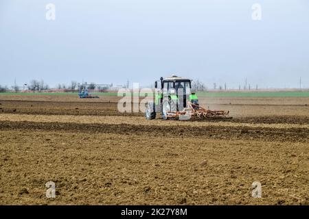 Lush and loosen the soil on the field before sowing. The tractor plows a field with a plow Stock Photo