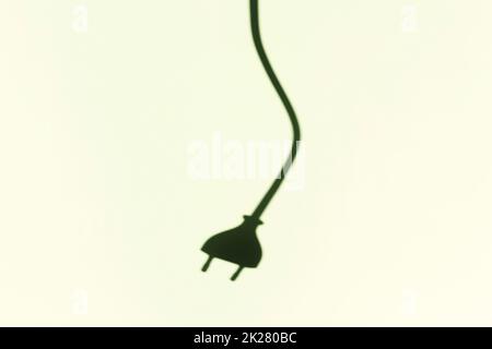 Shadow of electric wire and plug on the wall. Electric power cord cable with European plug Stock Photo