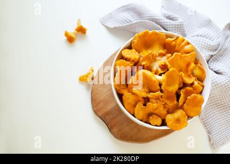 red chanterelle mushrooms in a white plate on a light gray table Stock Photo