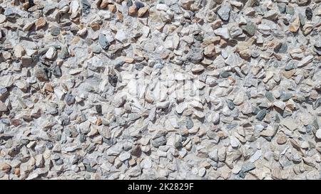 Pebbles Rubble In the cement courtyard. Dirty cracked old grunge vintage light gray concrete and cement mold texture wall or floor background with weathered paint and scratches Stock Photo