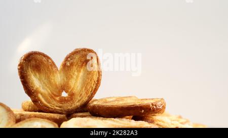 Fresh puff pastry palm cookies in the shape of a heart. Classic French pastries. Pig ear, elephant ear cookies, French hearts. Stock Photo