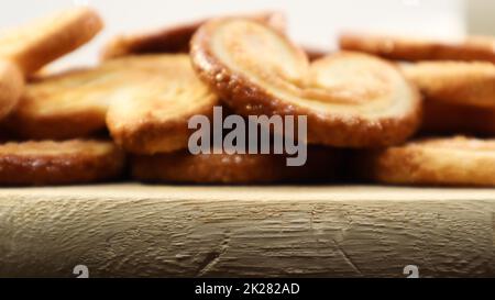 Fresh puff pastry palm cookies in the shape of a heart. Classic French pastries. Pig ear, elephant ear cookies, French hearts. Stock Photo
