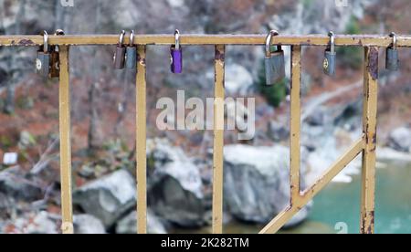 Many different locks hanging on the fence. The closed lock on the bridge - wedding tradition Stock Photo