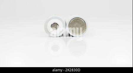 Two alkaline batteries on a white background with reflection. Energy supply and recycling concept. Copy space. Minimalism. Eliment AA is the most common type of galvanic batteries and accumulators. Stock Photo