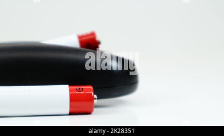 Black TV remote control with AAA alkaline batteries on a white background. Battery replacement, spare parts. Close up of the battery compartment of the remote control. Stock Photo