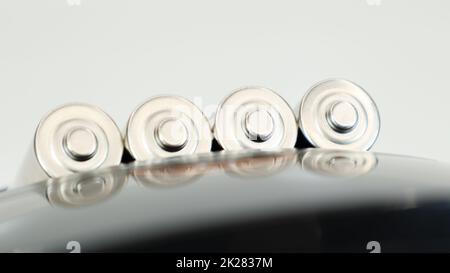 Rechargeable alkaline batteries in a battery charger on a white background. AA fast charger in black. The battery is charging. Stock Photo