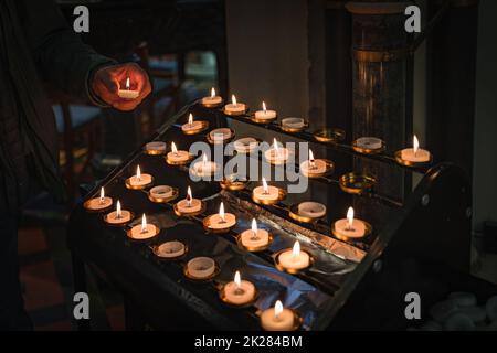 Mens hand holding a lit candle and putting it on altar, St. Patricks Cathedral, Ireland Stock Photo