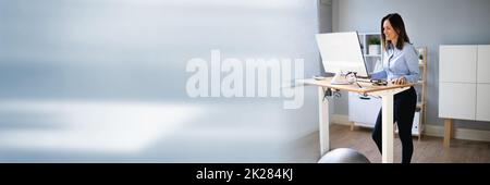 Woman Using Adjustable Height Standing Desk In Office Stock Photo