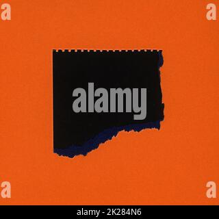 torn orange paper with black hole Stock Photo