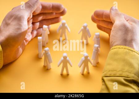 Businessperson's Hand Protecting Person Figures Stock Photo