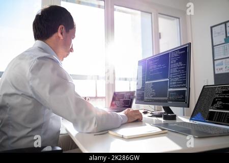 Coder Using Computer At Desk Stock Photo