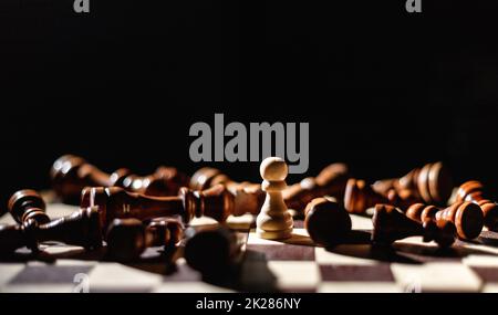 Winner white pawn surrounded by lying black chess. Leadership, strength and confidence concept Stock Photo