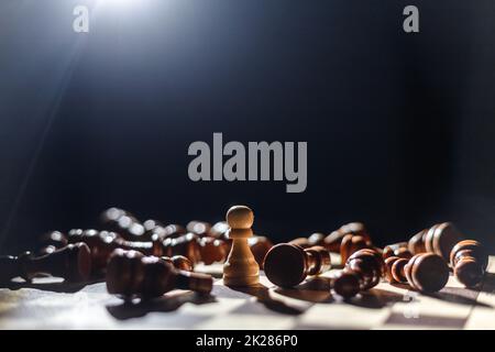 Winner white pawn surrounded by lying black chess. Leadership, strength and confidence concept Stock Photo