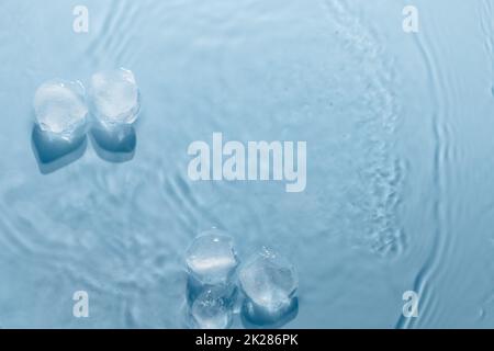 Ice cubes with water drops scattered on a blue background, top view. Stock Photo