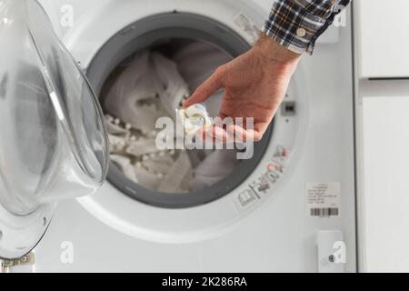 Gel caps in hand for washing machine, liquid coloured detergent and conditioner Stock Photo