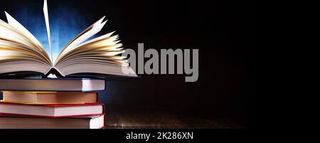 A composition with an open book lying on a stack of other books Stock Photo