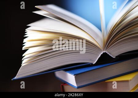 A composition with an open book lying on a stack of other books Stock Photo