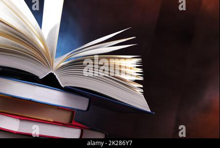 A composition with an open book lying on a stack of other books Stock Photo