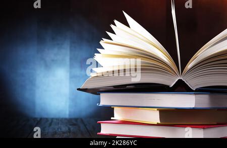 A composition with an open book lying on a stack of other books Stock Photo