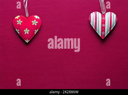 Two white pink metal hearts on a dark pink paper background Stock Photo