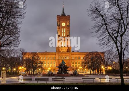 The famous Rotes Rathaus in Berlin at night in winter witrh some barren tree branches Stock Photo