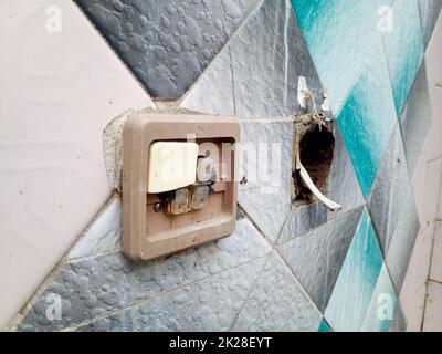 Switches on the old wall. Broken socket and switch. Stock Photo