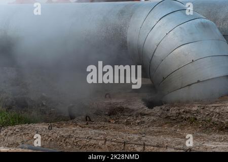 A large water pipe has burst and thick steam is coming out.A broken hot water or heating pipe.Urban communications and drainage systems.Dirty air from sewage systems and water supply.Rupture pipes Stock Photo