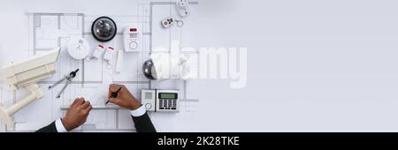 African Security Engineer Working On Home Alarm Blueprint Stock Photo