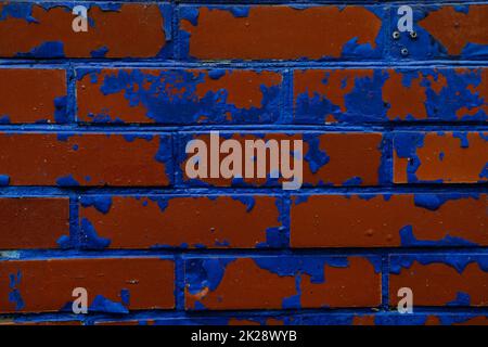 Colorful wall background with damaged paints of blue on red bricks Stock Photo
