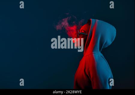 Casual hipster woman in hood blowing smoke Stock Photo
