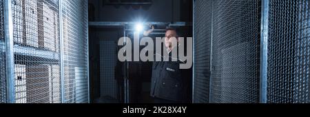 Security Guard With Flashlight At Night In Warehouse Stock Photo
